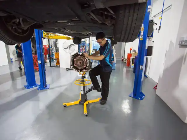 Gearbox being removed from a car on a transmission jack